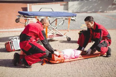 Paramedics putting injured girl onto a backboard on street